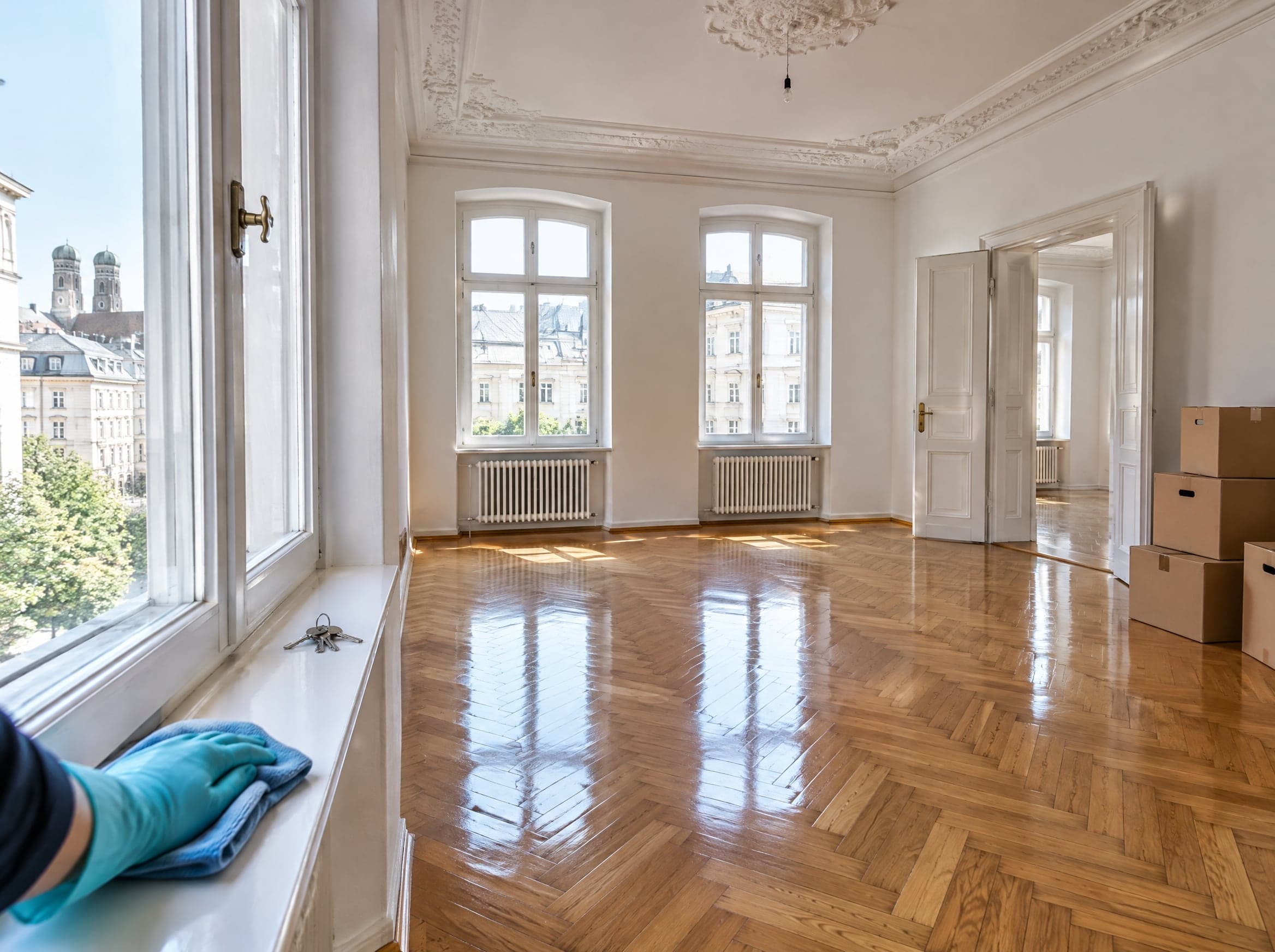 Endreinigung München: leere, frisch gereinigte Altbauwohnung mit Parkett, Umzugskartons und Schlüsseln auf der Fensterbank (KI-generiertes Symbolbild)
